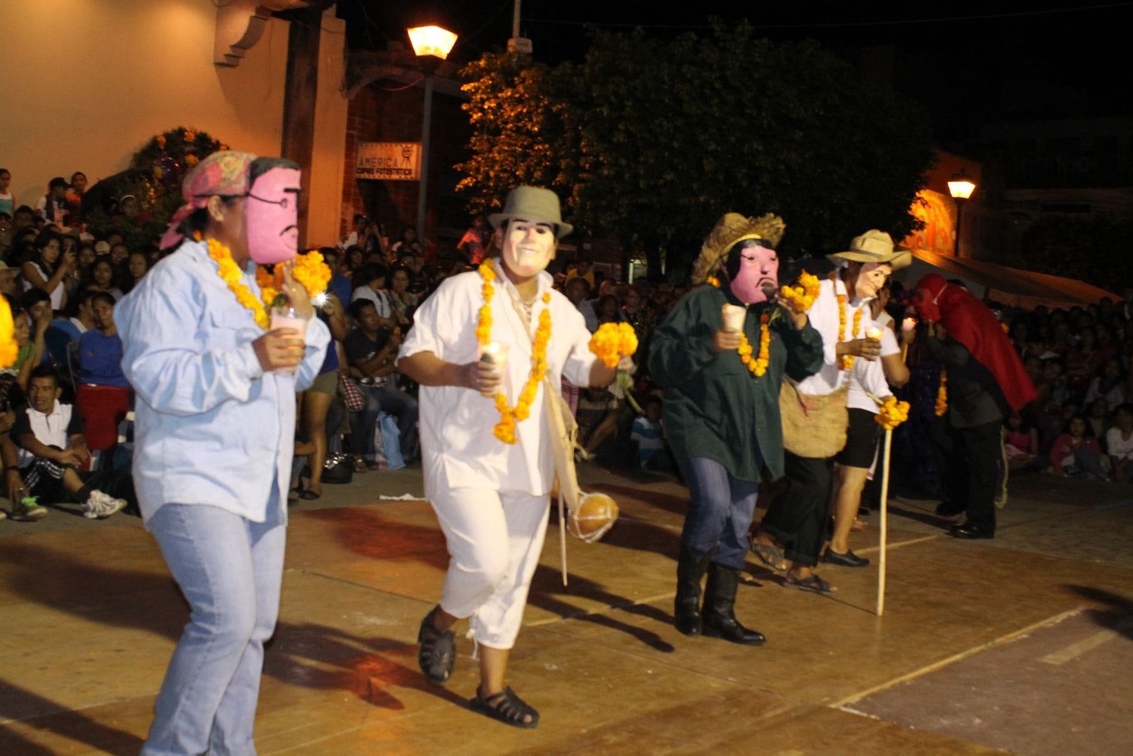 Comparsa de huehues con máscaras y collares de cempasúchil bailando de noche durante el Xantolo en la Huasteca Potosina